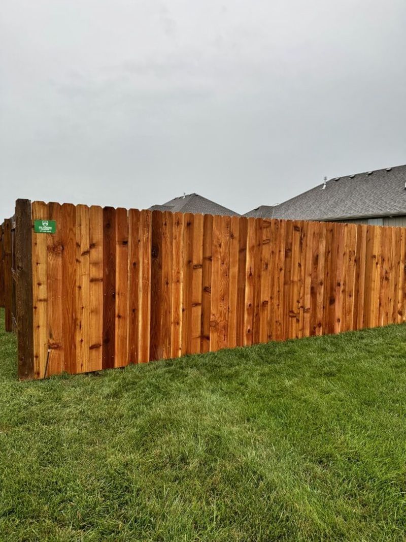 A wooden fence is sitting in the middle of a lush green field.