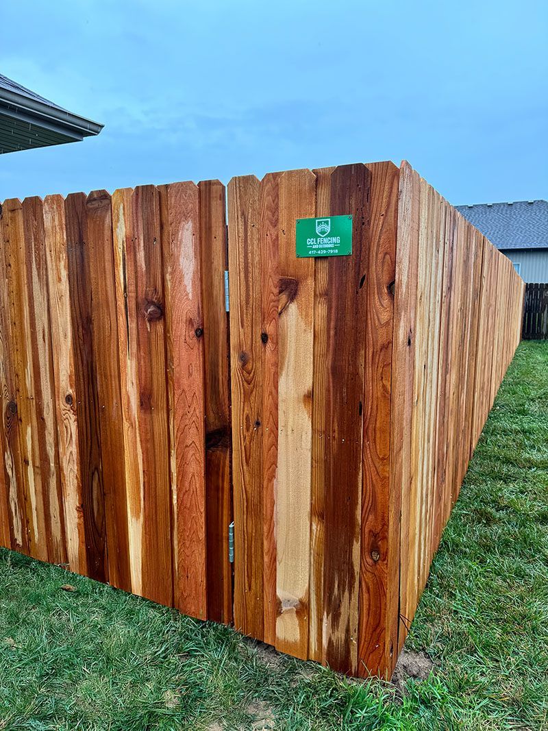A wooden fence is sitting in the grass next to a house.