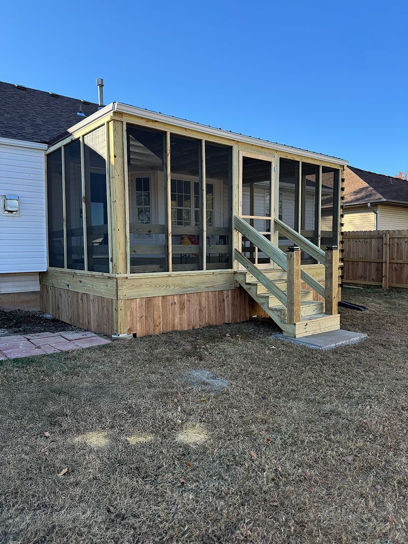 A screened in porch with stairs is in the backyard of a house.