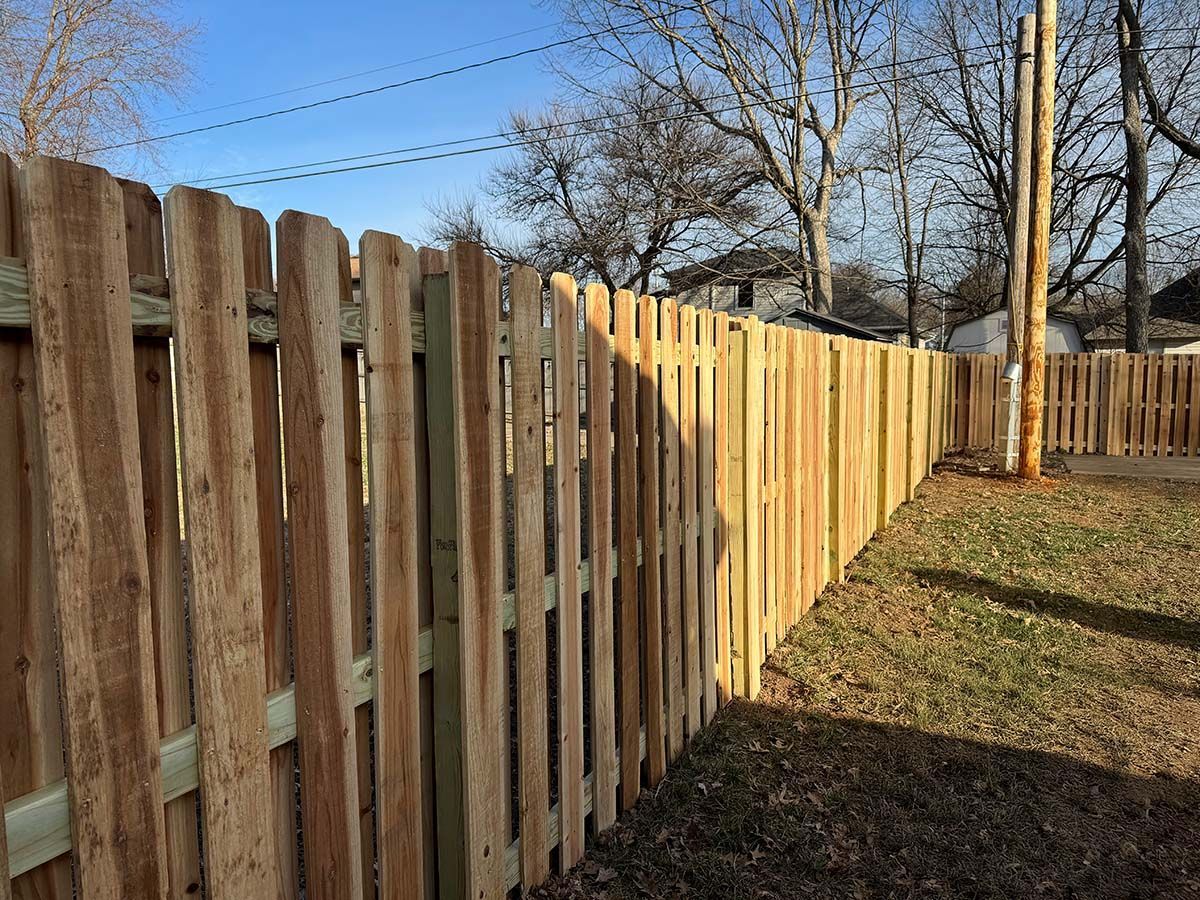 A wooden fence is sitting in the middle of a yard.