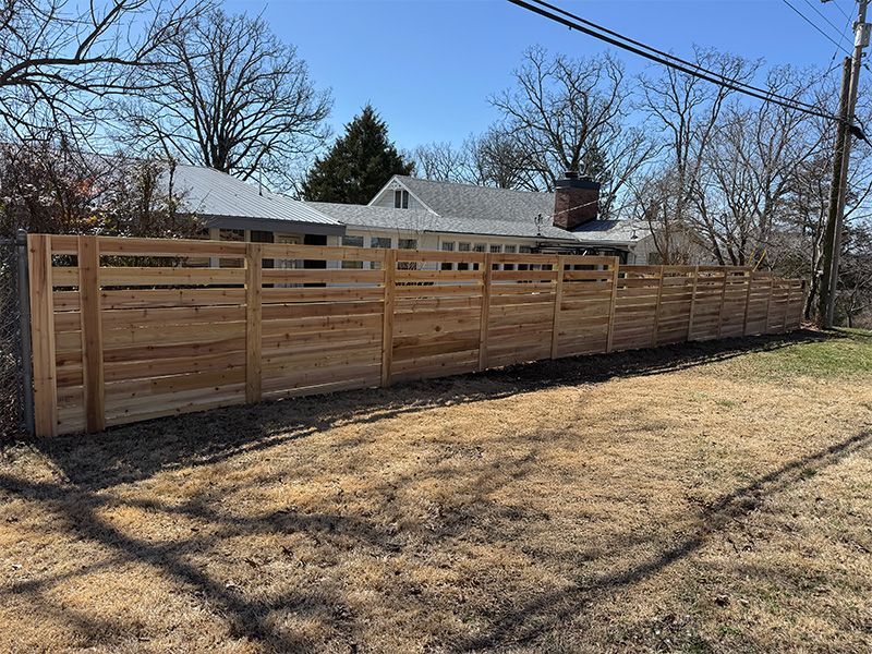 A wooden fence is in the backyard of a house.