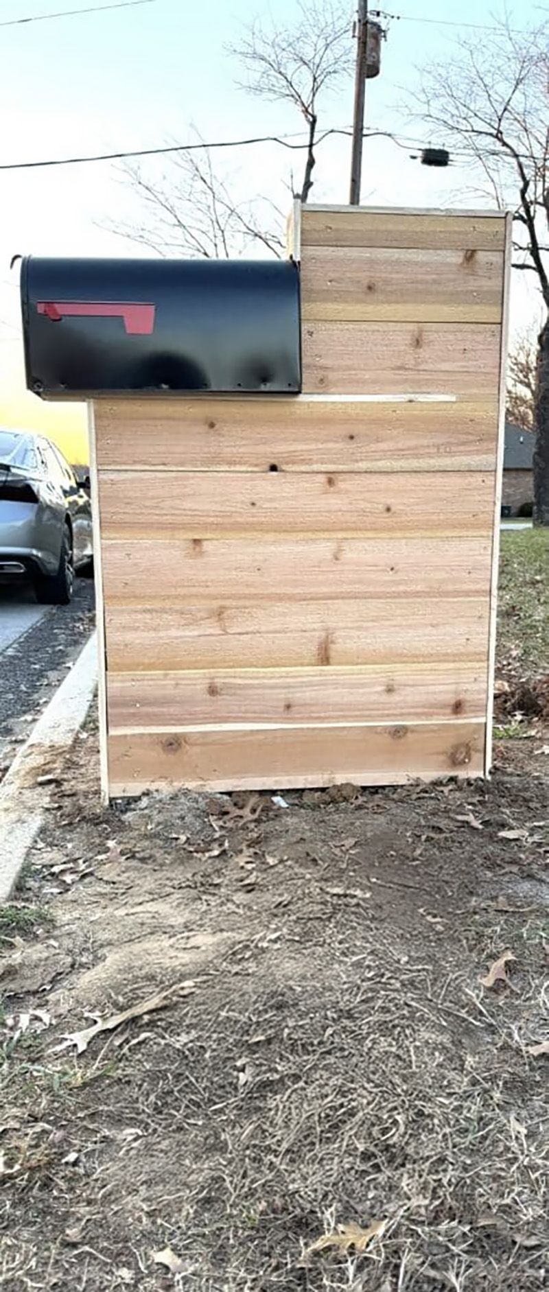 A wooden shed with a mailbox on top of it.