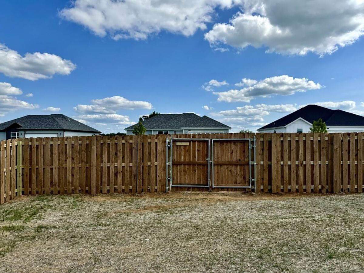A wooden fence with a gate in front of a house.
