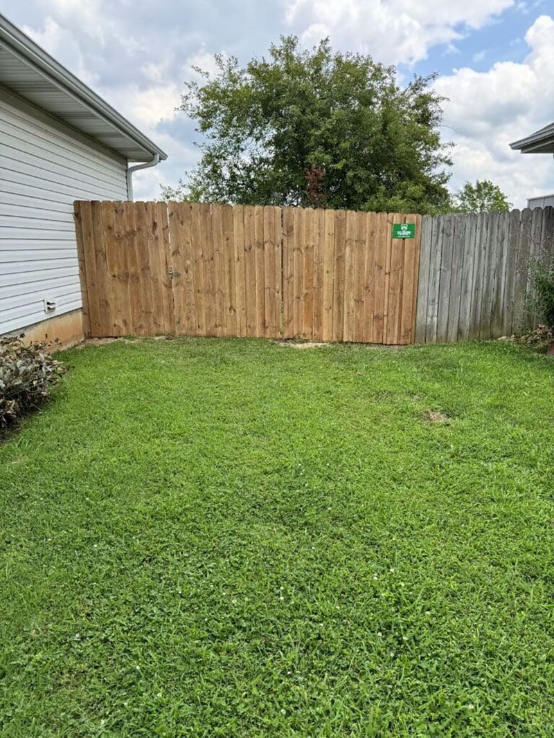There is a wooden fence in the backyard of a house.