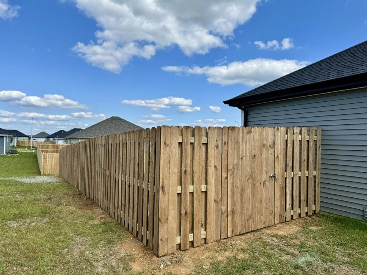 A wooden fence is in the backyard of a house.