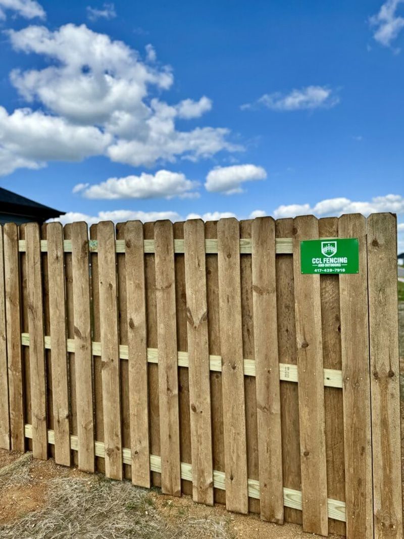 A wooden fence with a green sign on it