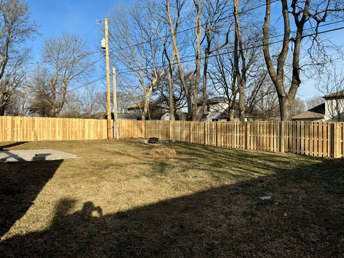 A backyard with a wooden fence and trees in the background.