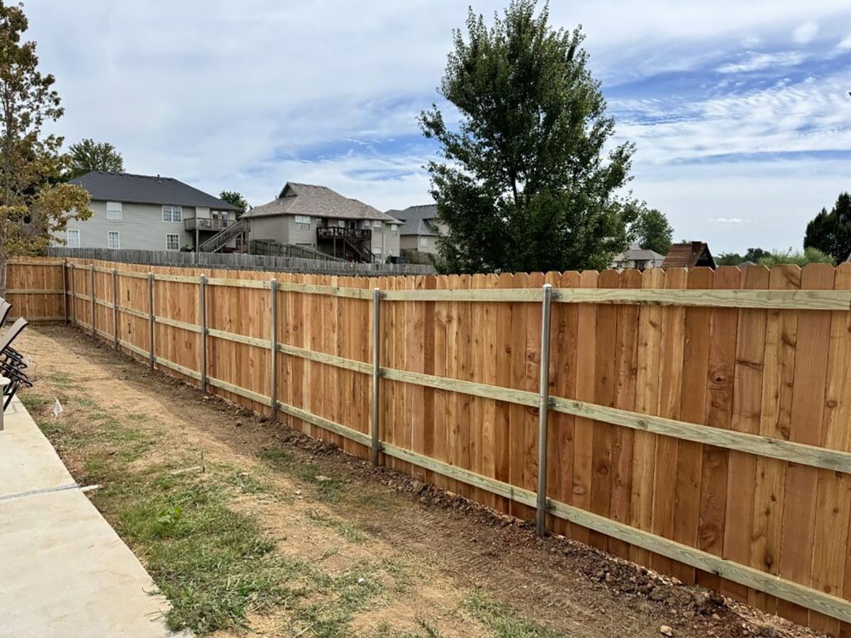 A wooden fence is in the backyard of a house.