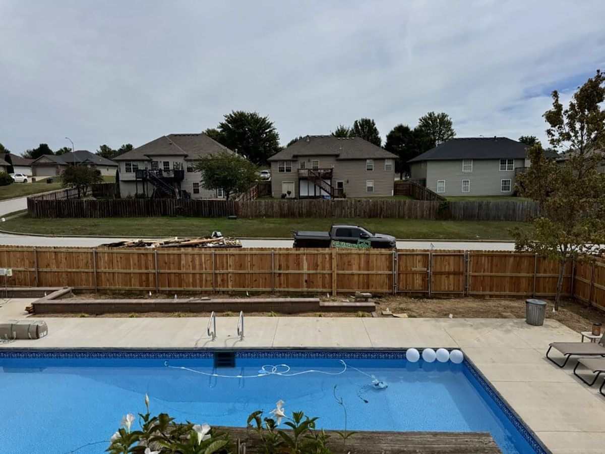 A large swimming pool is surrounded by a wooden fence.