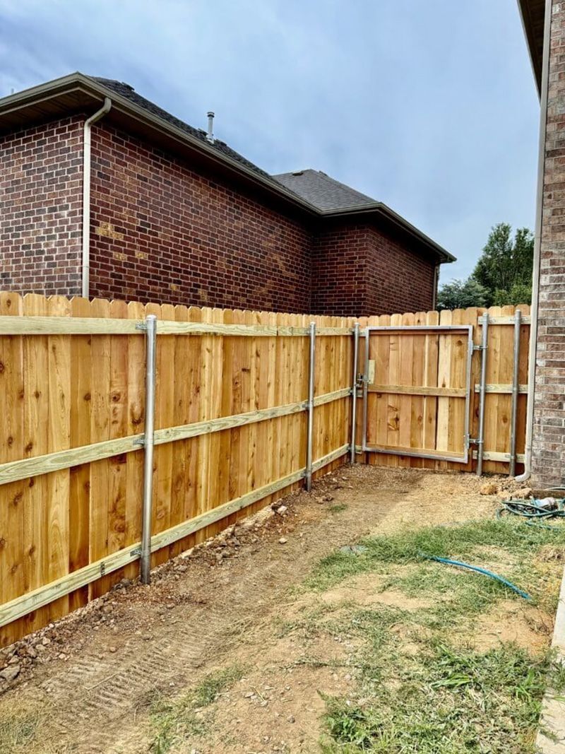 A wooden fence is being built in the backyard of a house.
