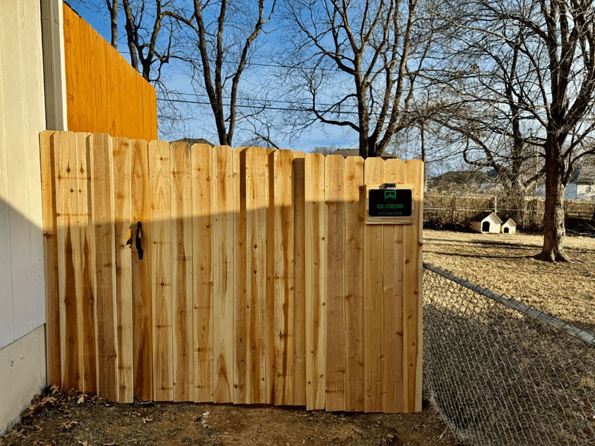 A wooden fence with a gate in the backyard of a house.