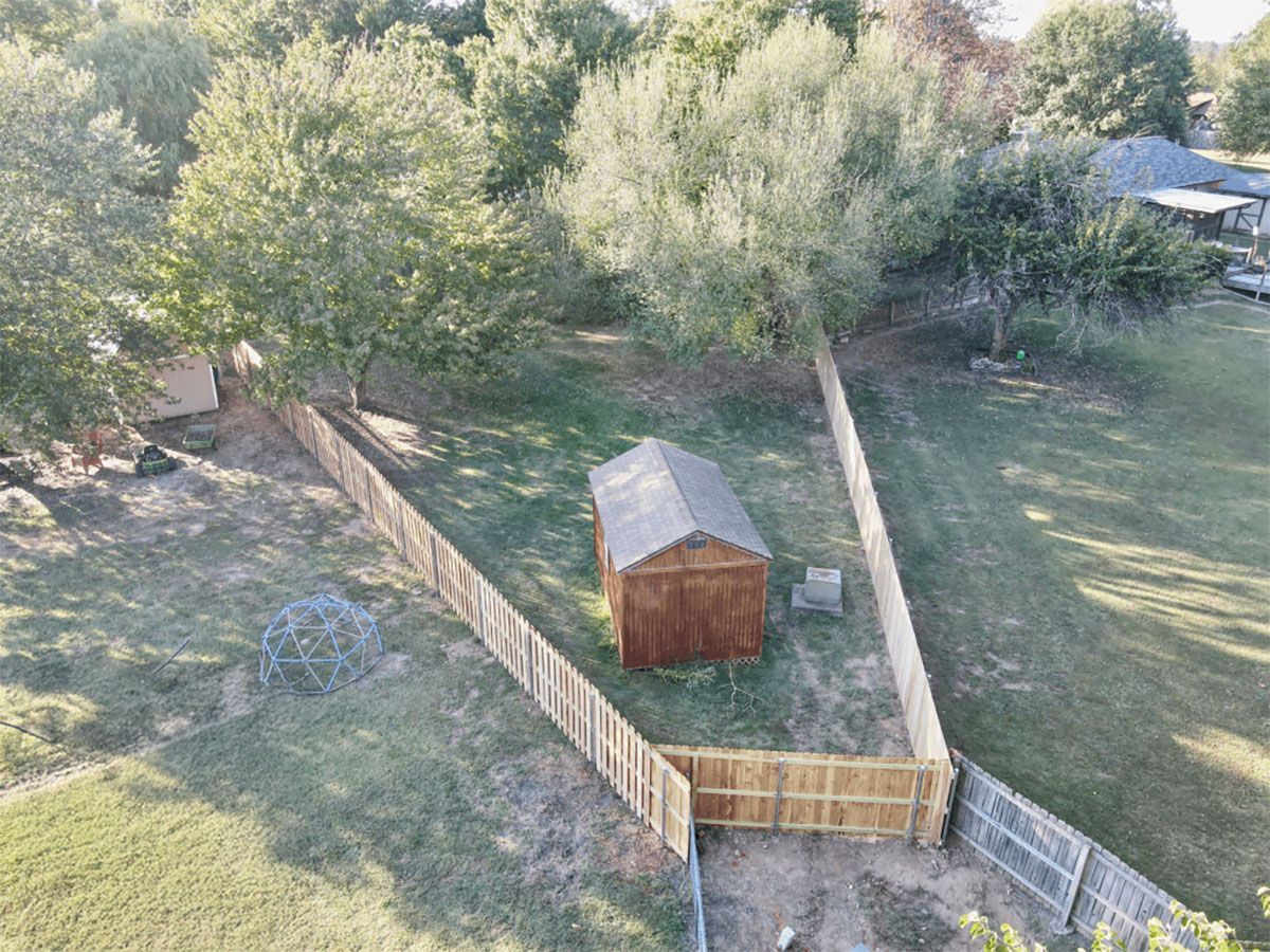 An aerial view of a backyard with a wooden fence and a shed.