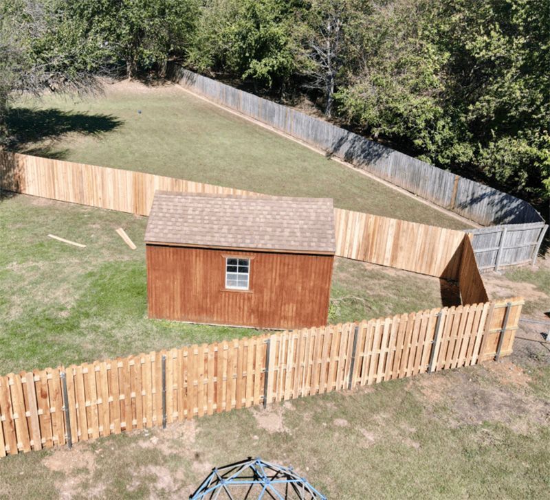 An aerial view of a backyard with a wooden fence and a shed