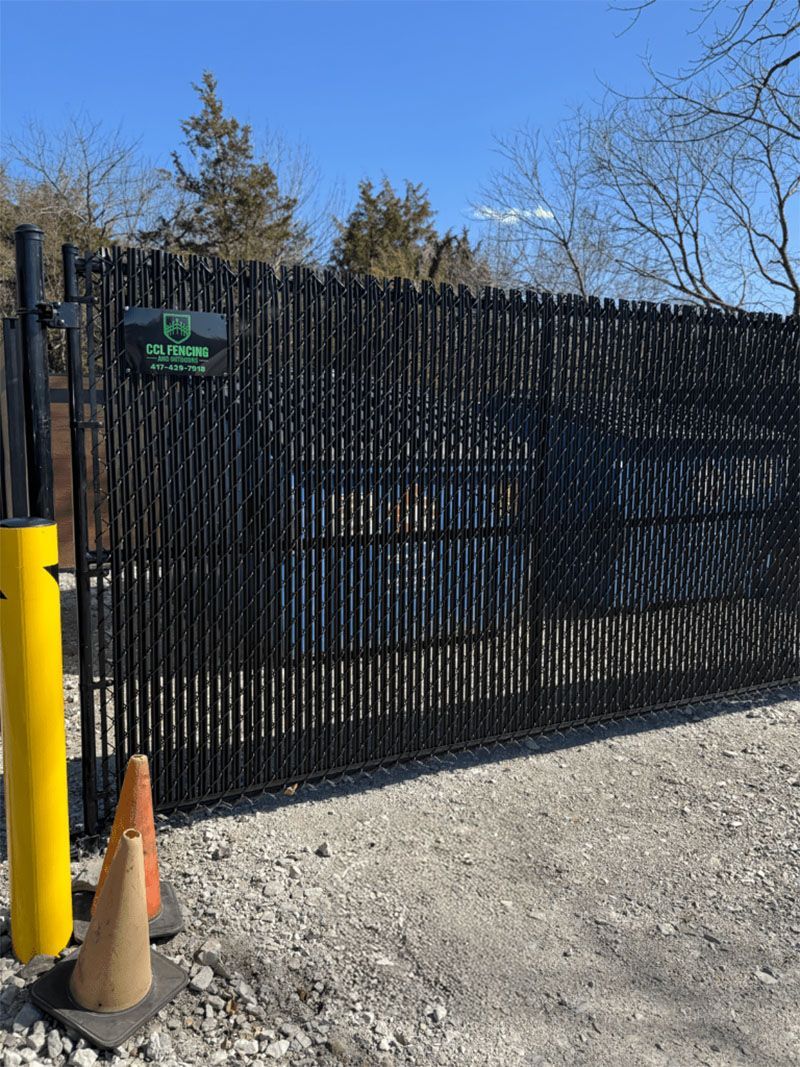 A fence with a yellow pole and cones in front of it