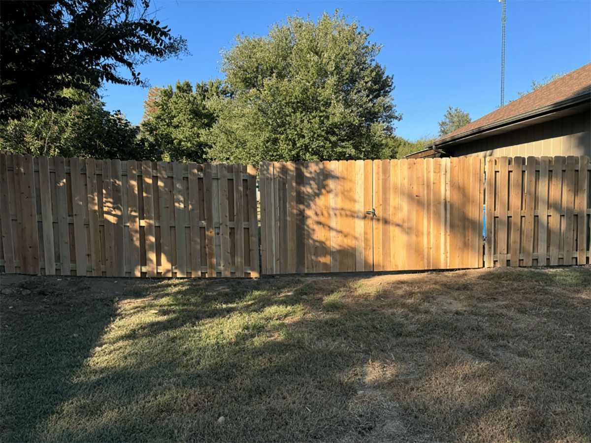 A wooden fence with a gate in the backyard of a house.