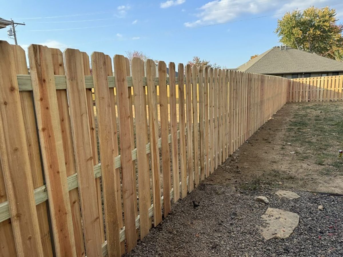 A wooden fence is in the backyard of a house.