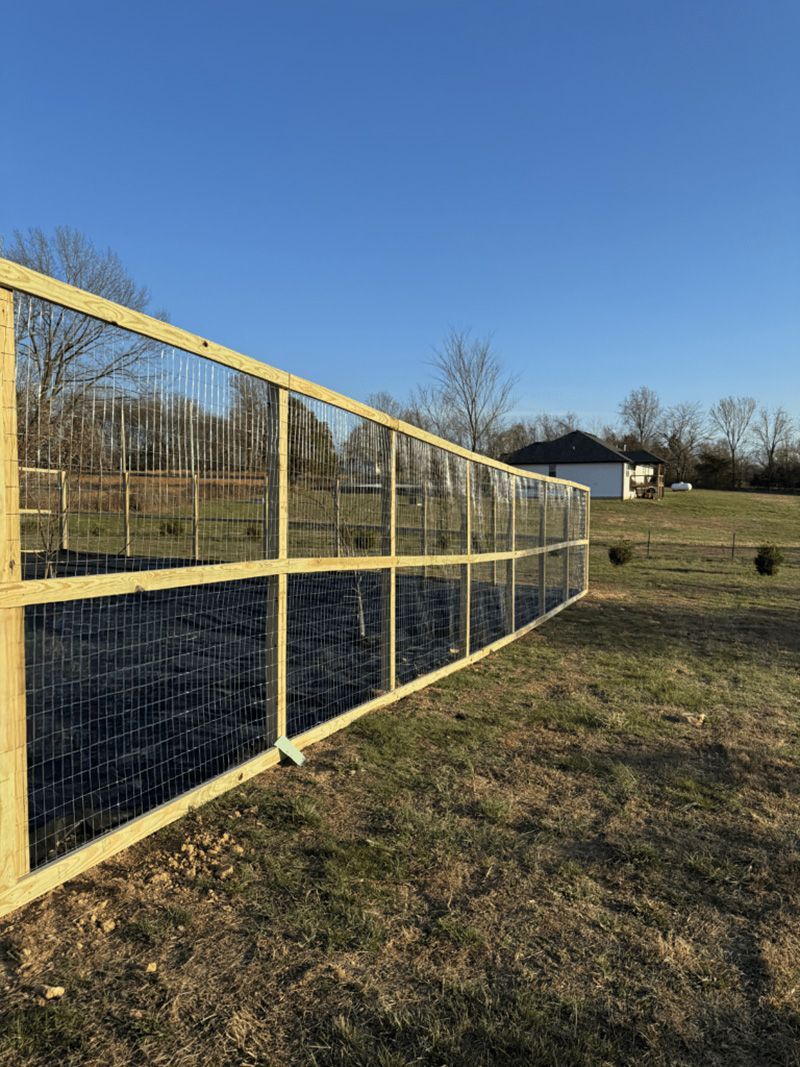 A wooden fence is sitting in the middle of a grassy field.