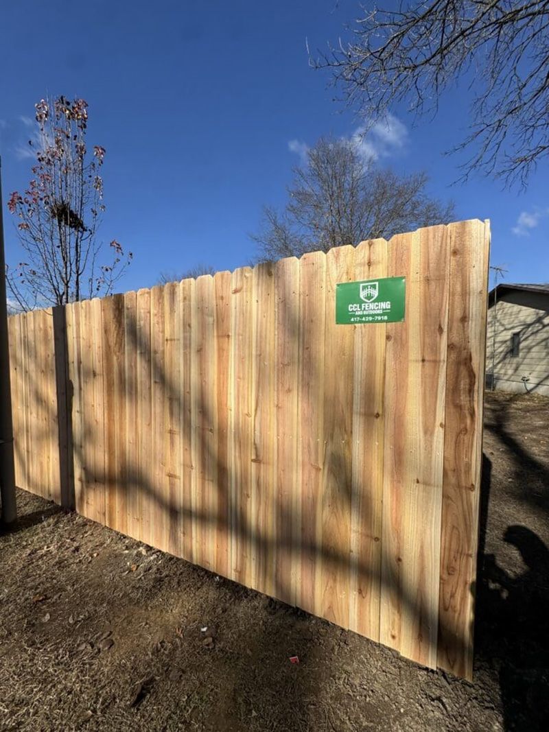 A wooden fence with a green sign on it.