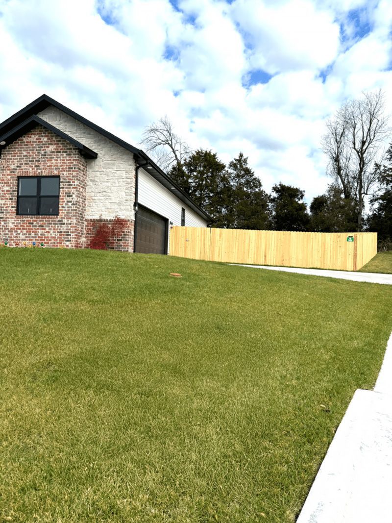 A brick house with a wooden fence in front of it.