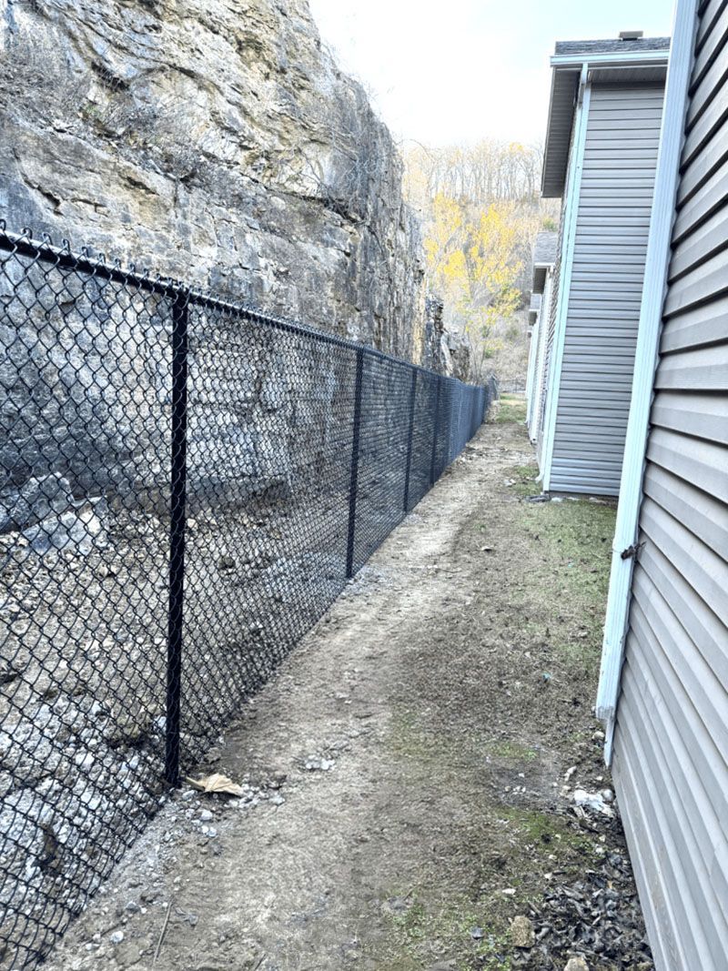 A chain link fence is along the side of a house.