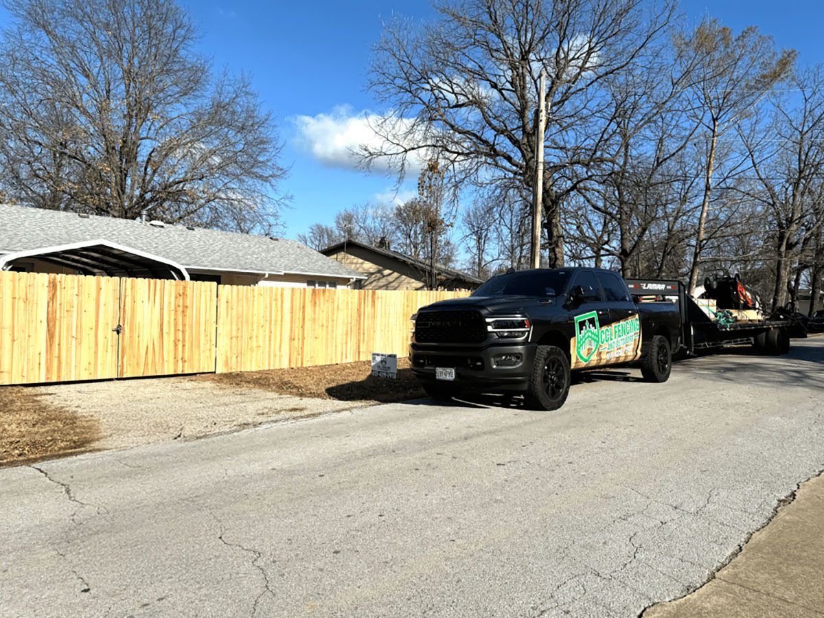 A truck is parked on the side of the road next to a wooden fence.