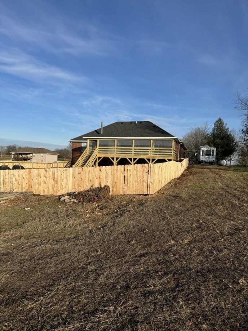 A house with a wooden deck and a wooden fence in front of it.