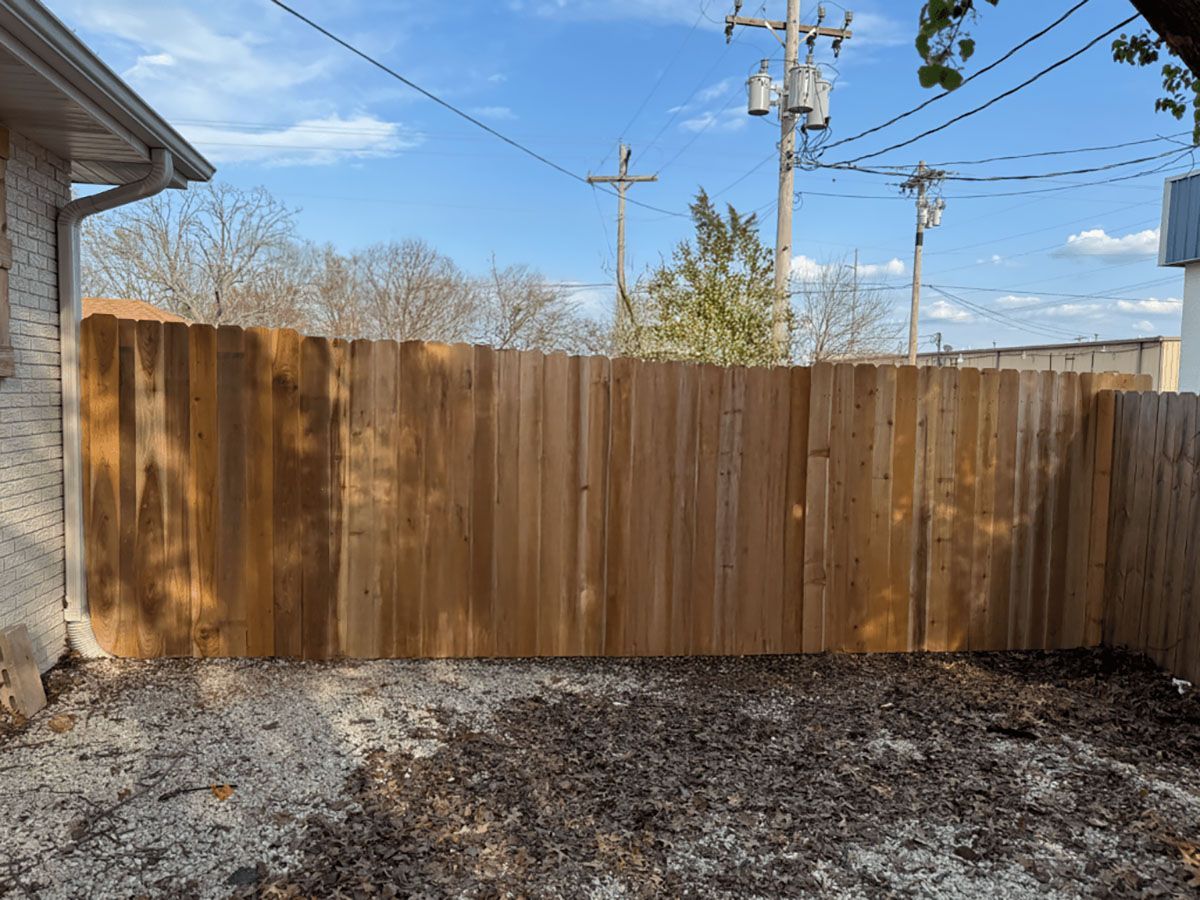 A wooden fence is in the backyard of a house.
