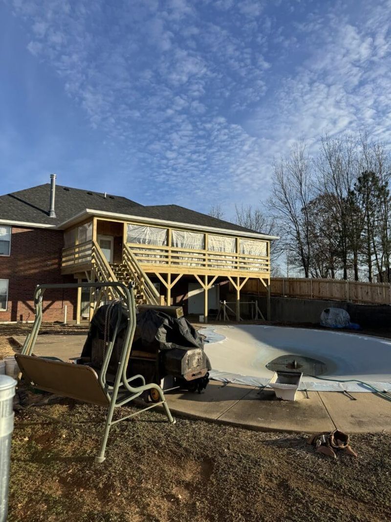A large house with a wooden deck and a swimming pool in the backyard.