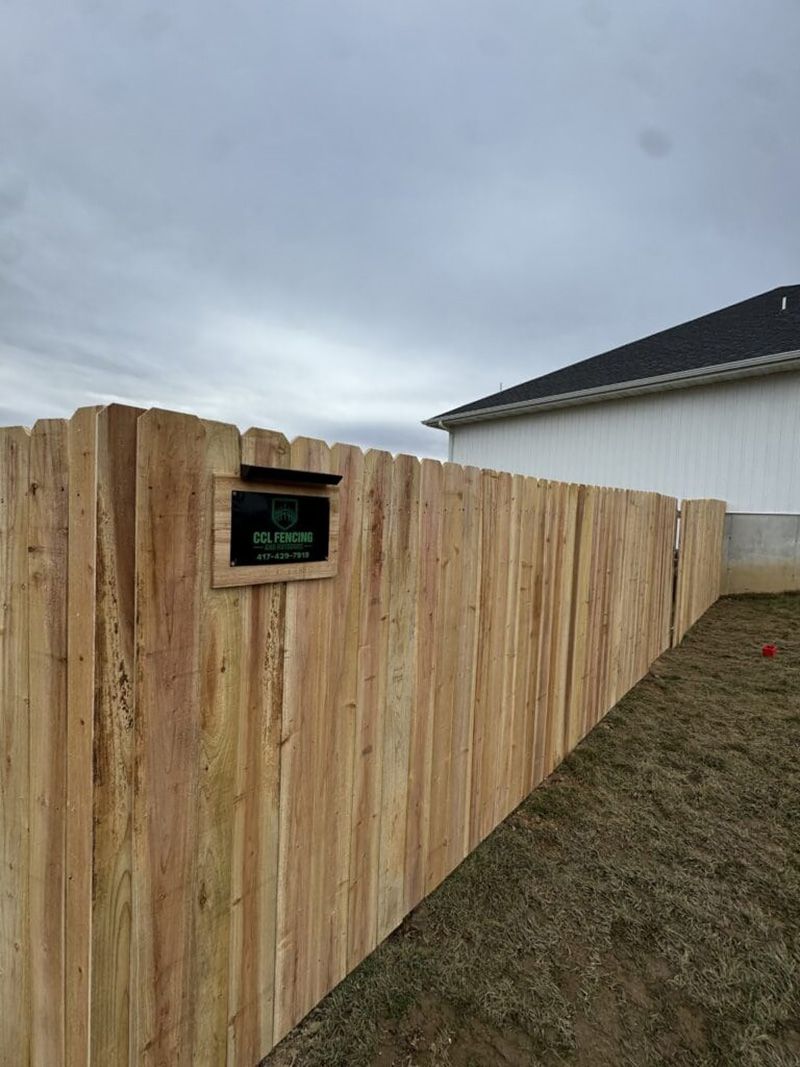A wooden fence with a mailbox in front of a house.