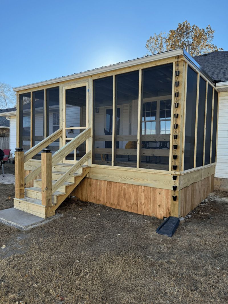 A screened in porch is being built on the side of a house.