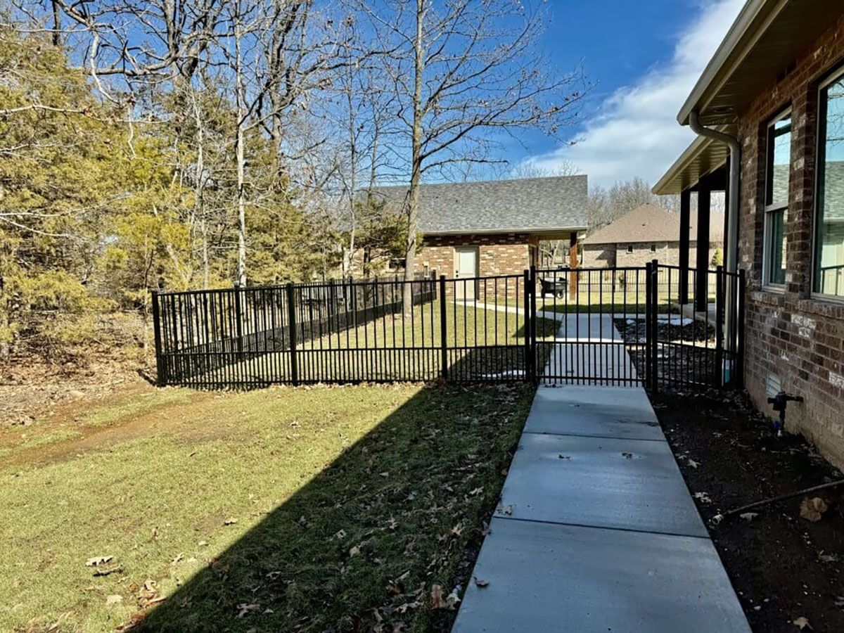 A brick house with a metal fence and a walkway leading to it.