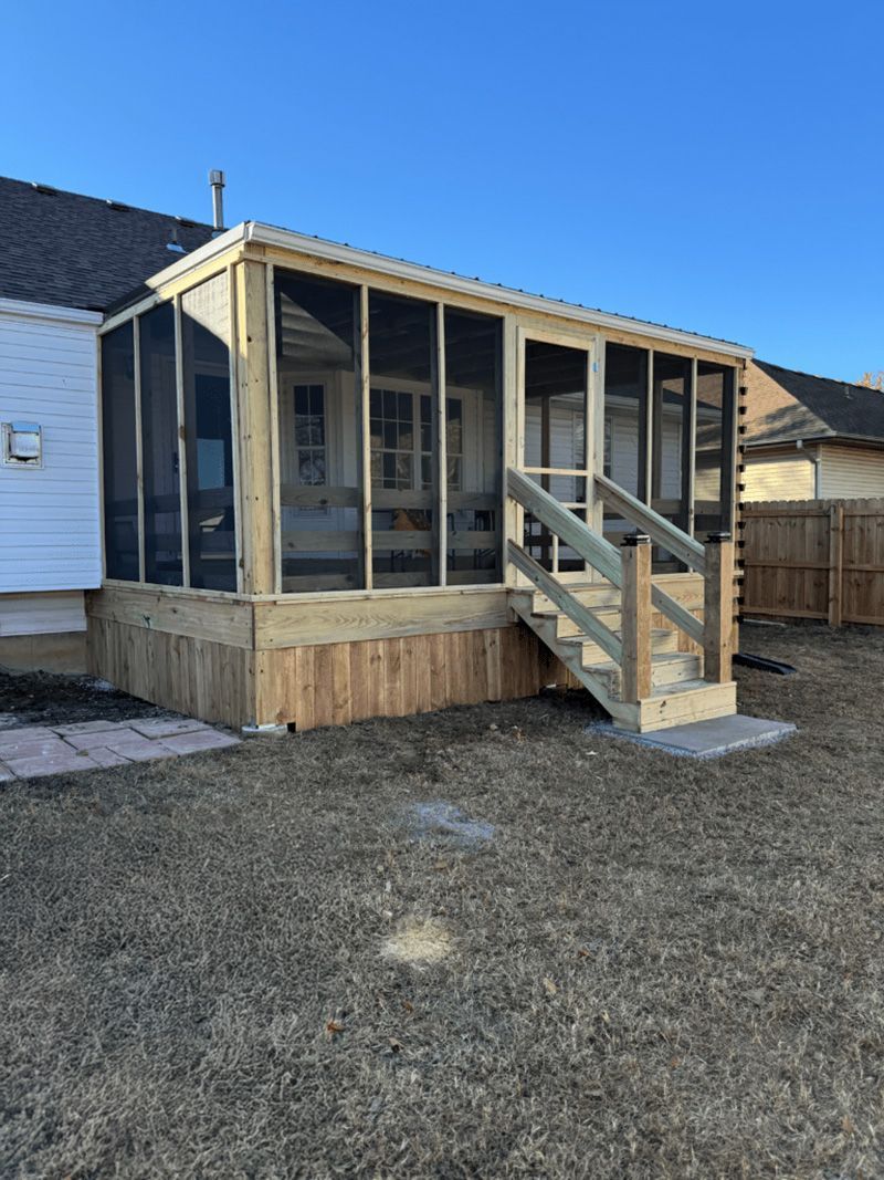 A screened in porch with stairs is in the backyard of a house.