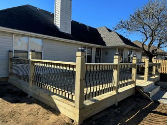 A wooden deck is sitting in front of a house.
