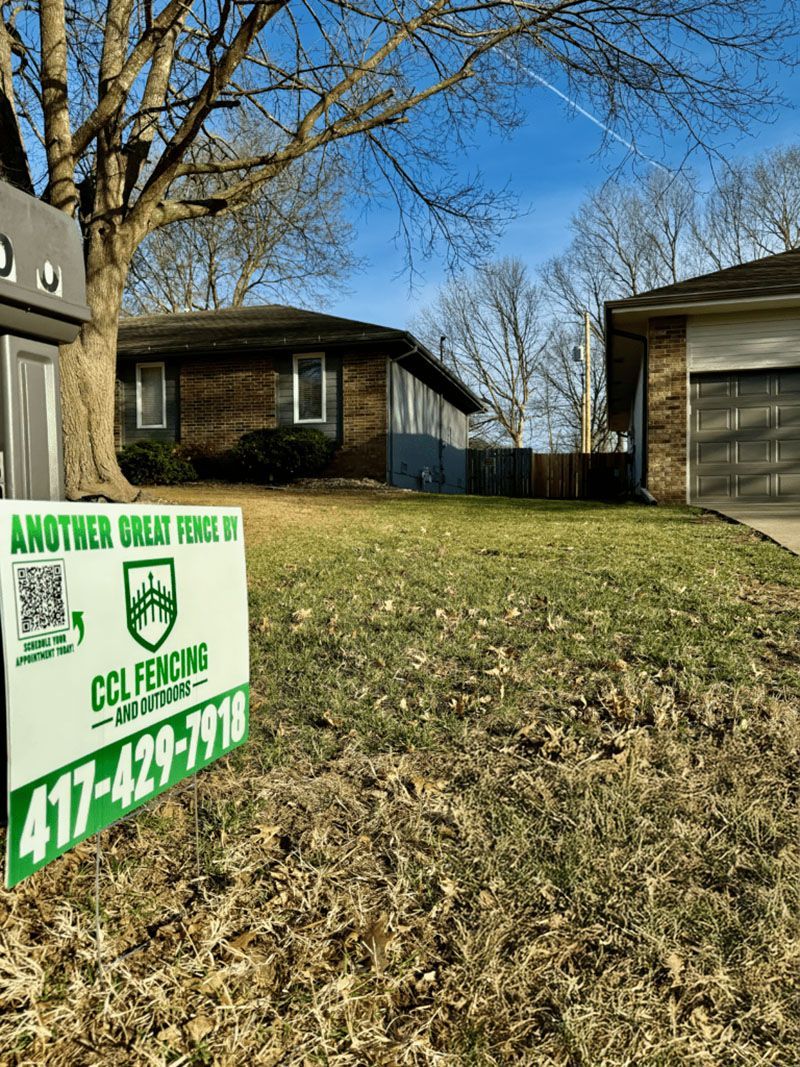 There is a sign in the grass in front of a house.