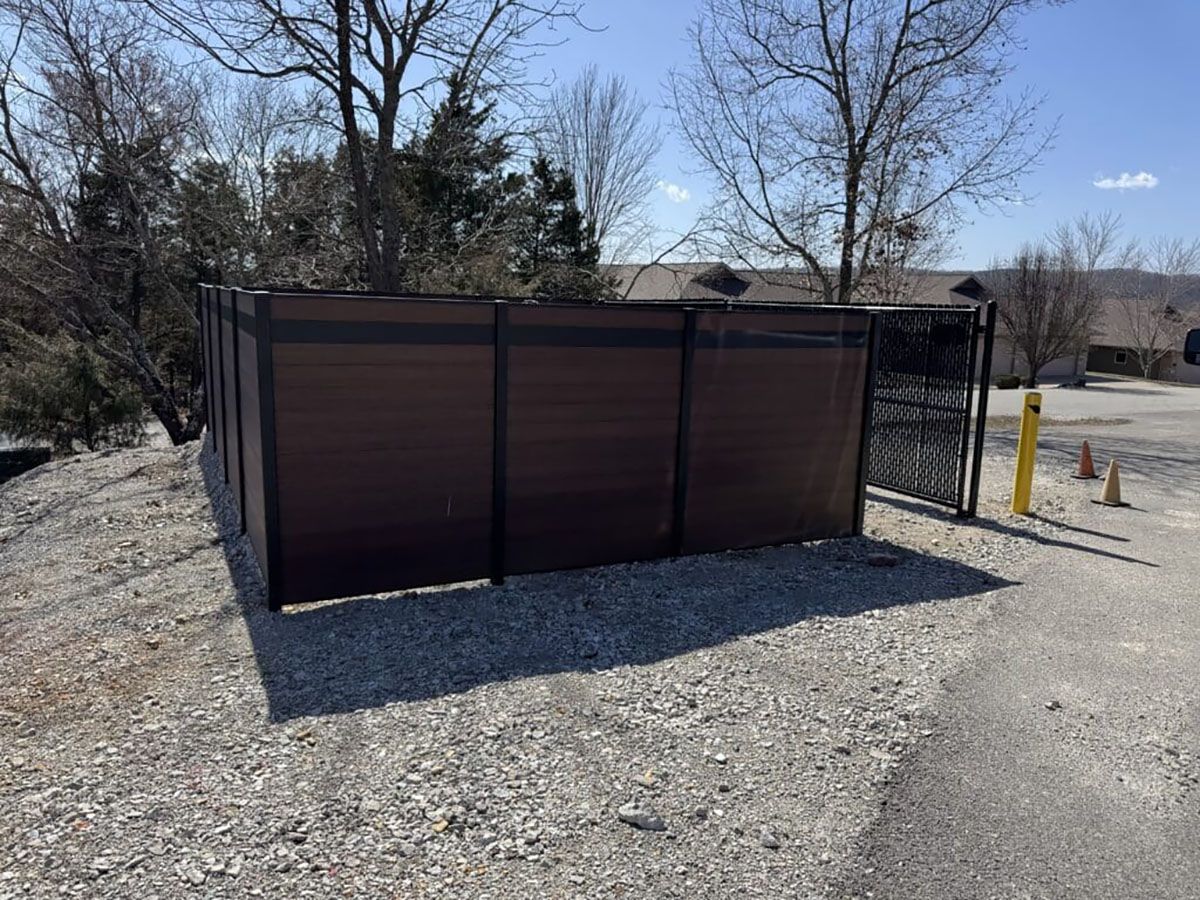A wooden fence is sitting in the middle of a gravel lot.