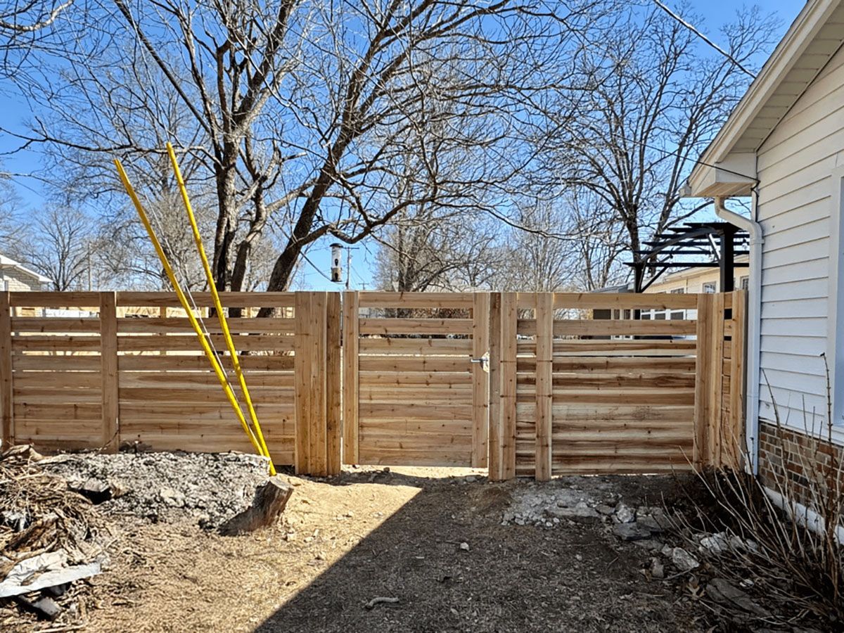 A wooden fence with a gate in the backyard of a house.