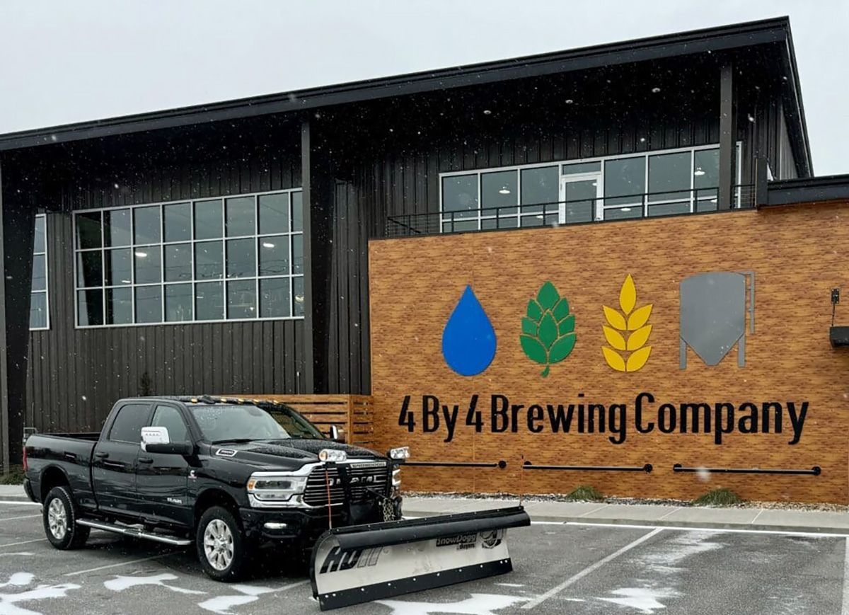 A truck is parked in front of a building that says 4 by 4 brewing company.