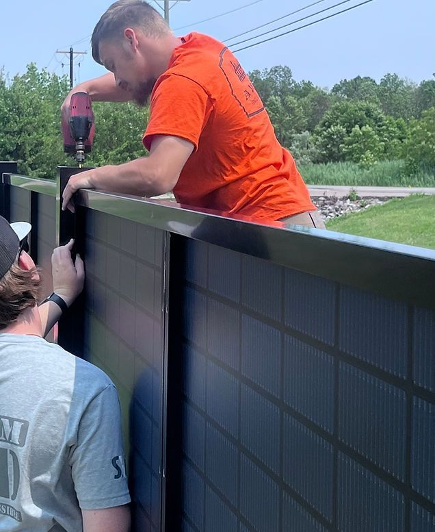 A man in an orange shirt is working on a solar panel