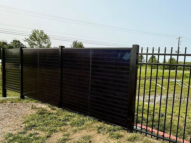 A black fence with a solar panel on it