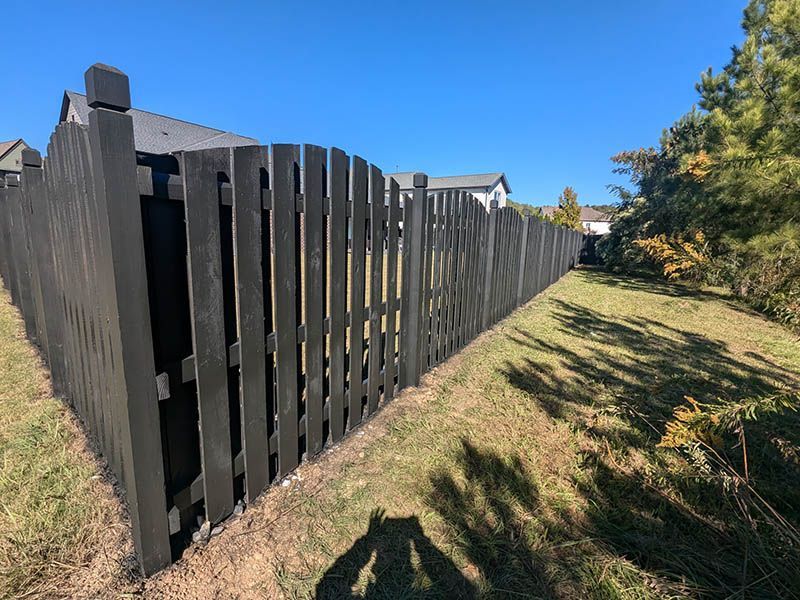A black wooden fence is sitting in the middle of a grassy field.