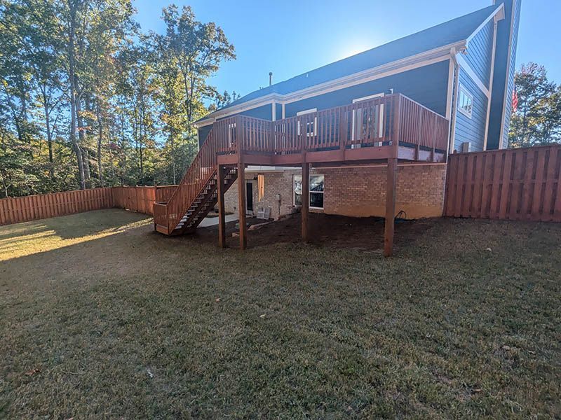 The backyard of a house with a large wooden deck and stairs.