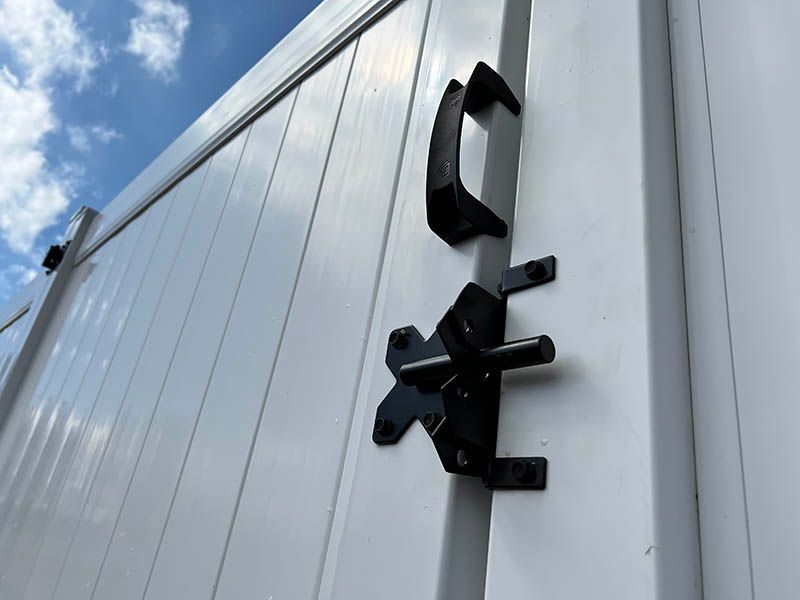A white fence with a black latch on it