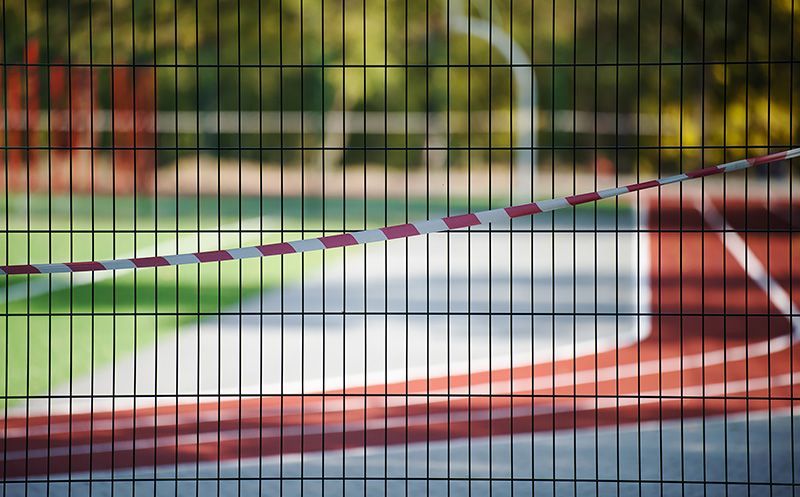 A fence with a red and white tape covering a basketball court.