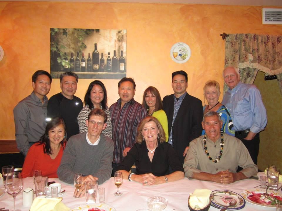 Group of people seated and standing in front of a table in a restaurant.