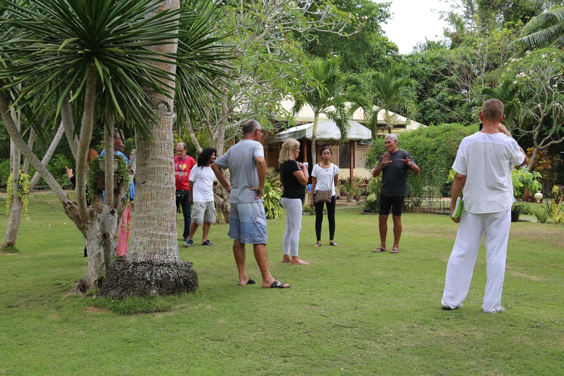 A group of people standing in a grassy yard, possibly on a guided tour.