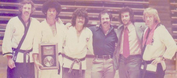 Six men pose together, some in martial arts uniforms.