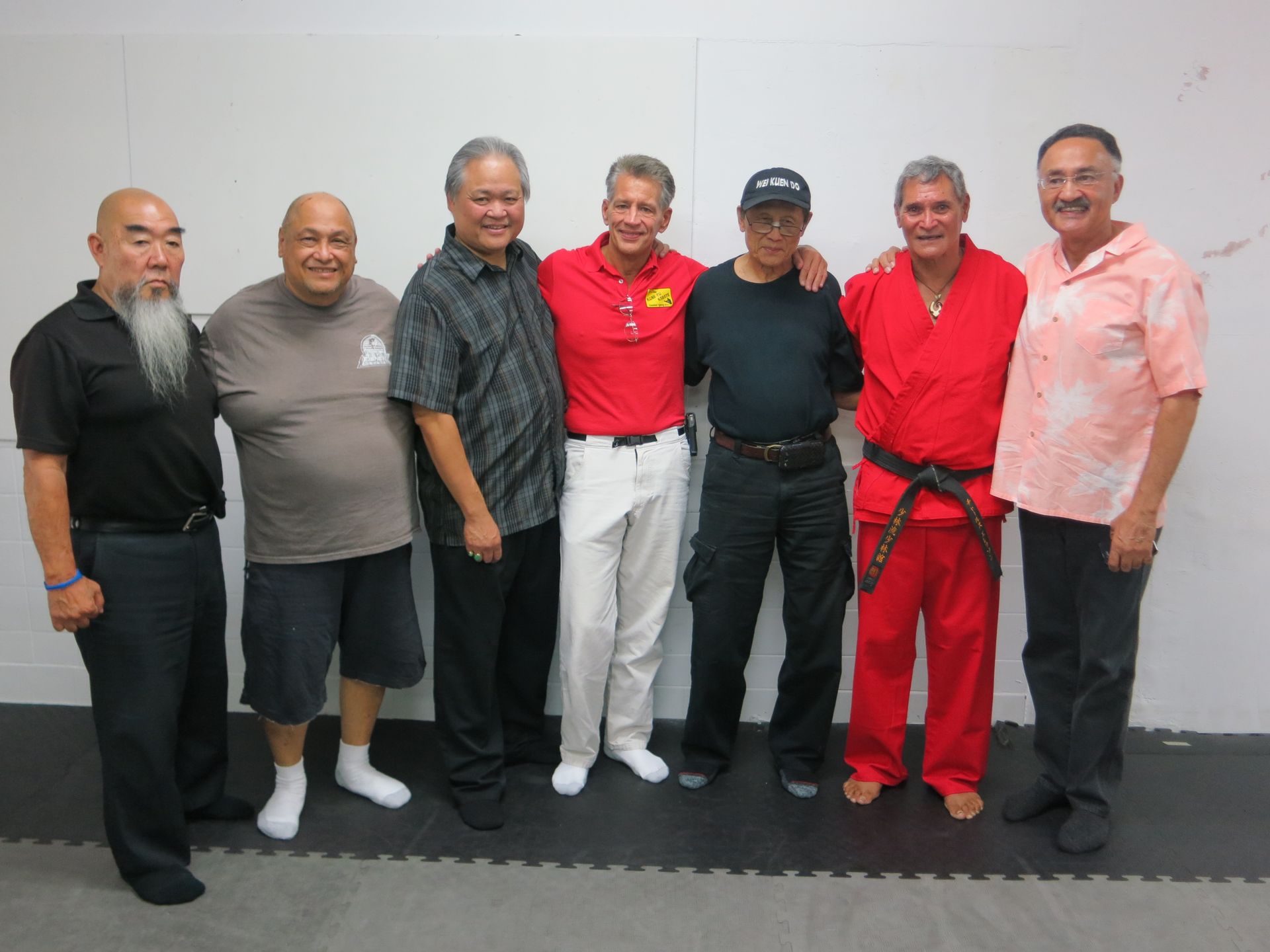 Group of men in a room, posing together. They're of varying ages, with some wearing martial arts attire.
