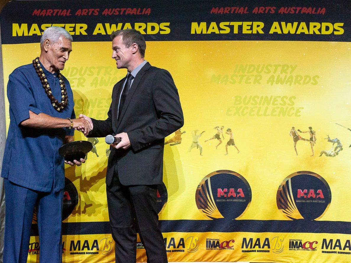 Two men shaking hands on a stage with a 