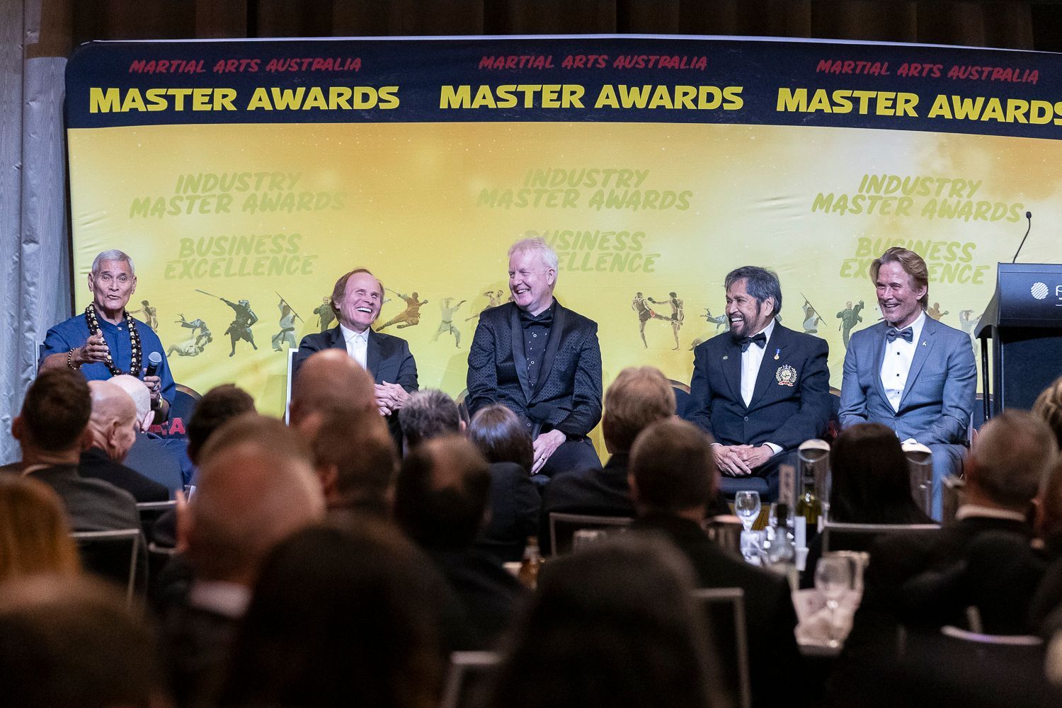 Panel of five men in formal attire at a 