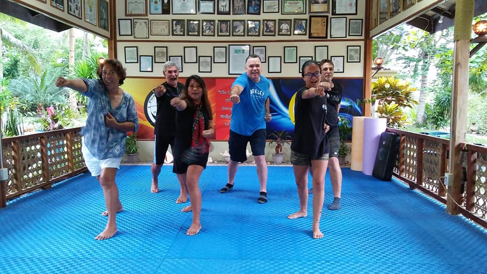 A group of six people practices martial arts in a pavilion.
